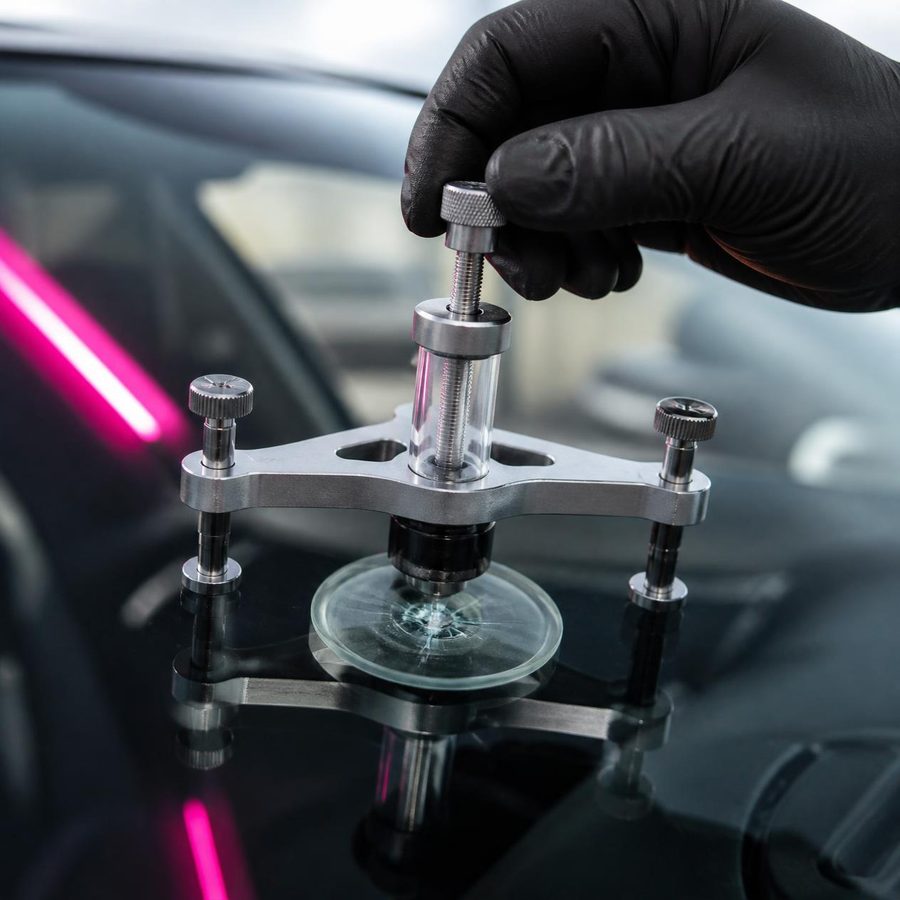Technician repairing a rock chip on a windshield with a resin injector bridge at Xtreme Auto Re-Stylin Center in Amarillo